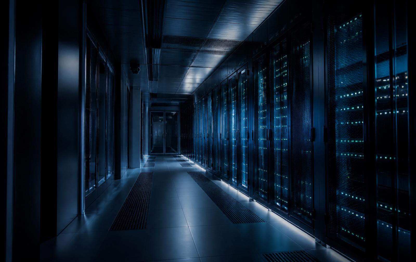Interior of a European data center at night, illuminated server racks receding into darkness